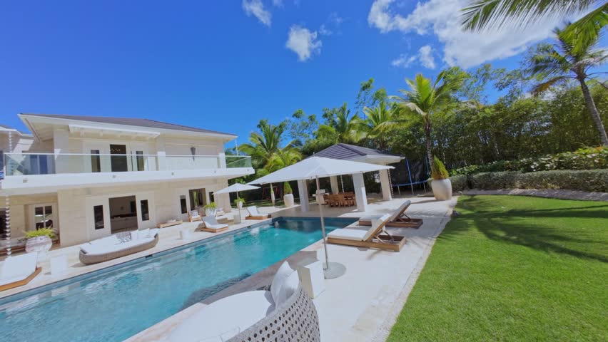 Luxury villa with pool, elegant outdoor lounge, and lush tropical garden. Aerial drone FPV