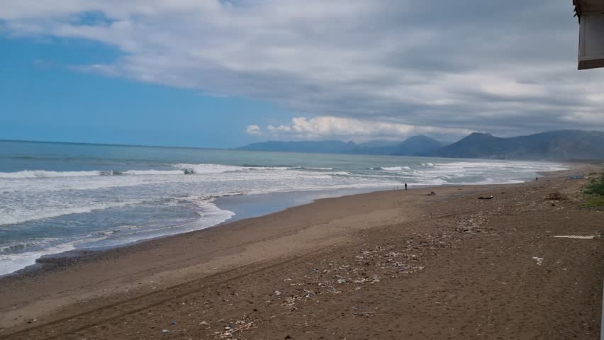 A deserted, windswept beach stretches along the Kabylie coastline in northern Algeria, its untouched beauty amplified by the quiet emptiness of the off-season. Waves crash gently against the shore