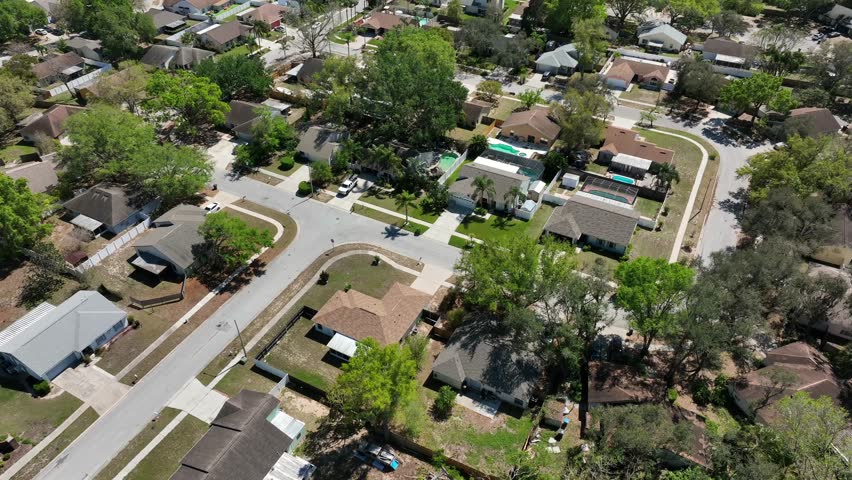 Suburban neighborhood in Florida with single-family homes,tree-lined streets and well-kept yards. One story houses with a mix of light-colored and brown-tiled roofs.Aerial top view. brandon,Florida.