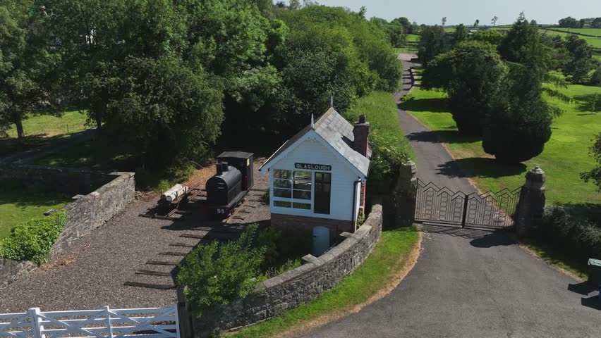 Old Signal Box, Glaslough, County Monaghan, Ireland, September 2022. Drone orbits clockwise around the preserved old Railway Building with a Replica Steam Train adjacent to the Level-Crossing.