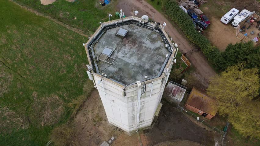 Aerial view drone high up water radio tower next to large river estuary drainage system in East England Lincolnshire fen farmland flat expansive land UK. 