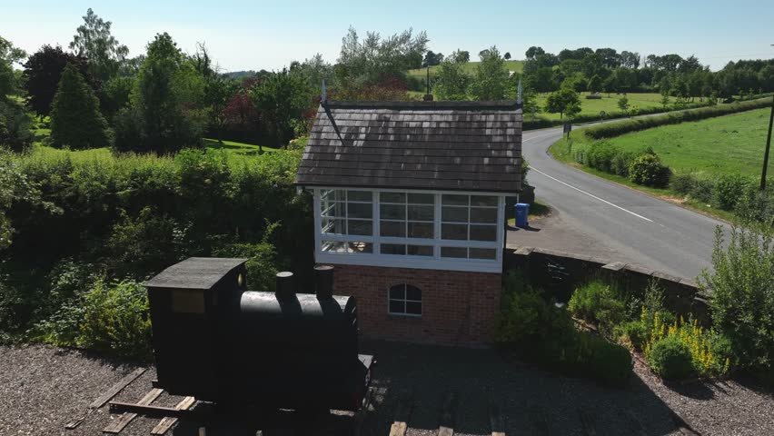 Old Signal Box, Glaslough, County Monaghan, Ireland, September 2022. Drone orbits counter clockwise above the renovated old Railway Building and replica Steam Train rising to reveal the slate roof.
