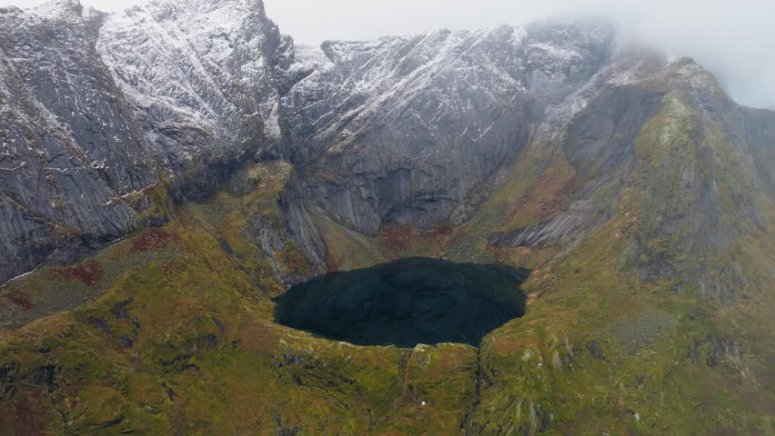 Reinevatnet above Reine village and Reinebringen hills, Lofoten islands, Drone shot