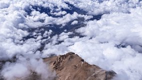 Mountain peak rising above thick cloud layer, golden sunlight illuminating rugged terrain, revealing expansive wilderness and dramatic geological landscape - Powered by Shutterstock - Get 15% off with code: PIKWIZARD15