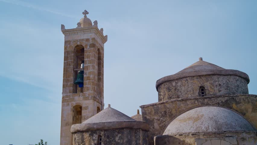 Beautiful ancient greek orthodox church from 9th century byzantine era in Cyprus. Stone bell tower with cross on top of it. Blue sky in small island of Cyprus. Religious and sacred chapel