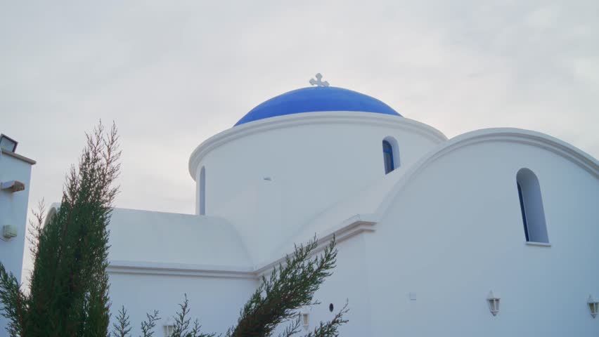 Small greek church or chapel with typical blue dome and white walls in Cyprus. Traditional greek orthodox little parish with a cross on top of dome on sunny day outdoors by the Mediterranean Sea