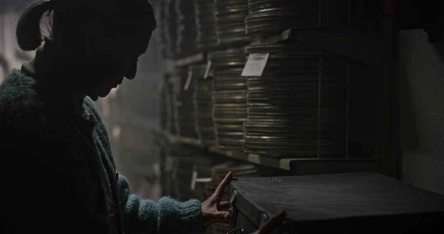 Elderly Woman Searching for Rare Film Reel in a Vintage Archive