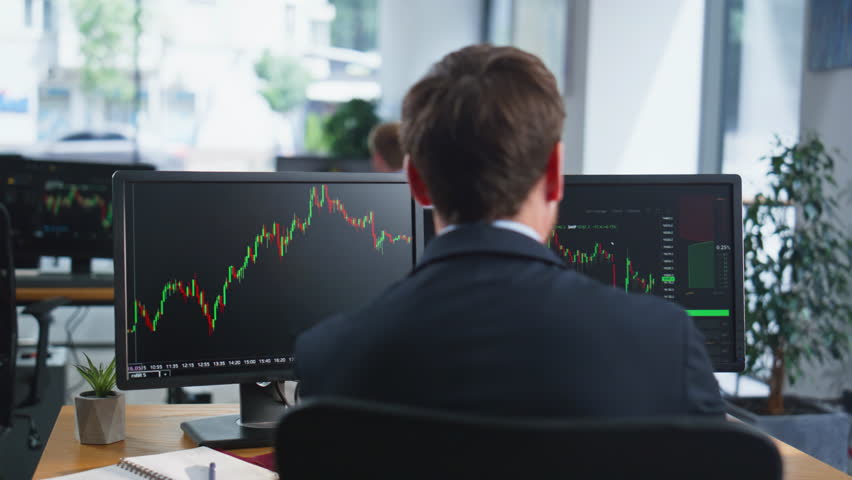 Stock trader looking monitors analyzing currency market charts in coworking workplace closeup. Bearded investor working at multiple computer screens. Businessman thinking on cryptocurrency investment.