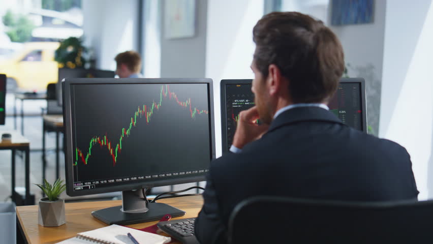 Stock trader looking monitors analyzing currency market charts in coworking workplace closeup. Bearded investor working at multiple computer screens. Businessman thinking on cryptocurrency investment.
