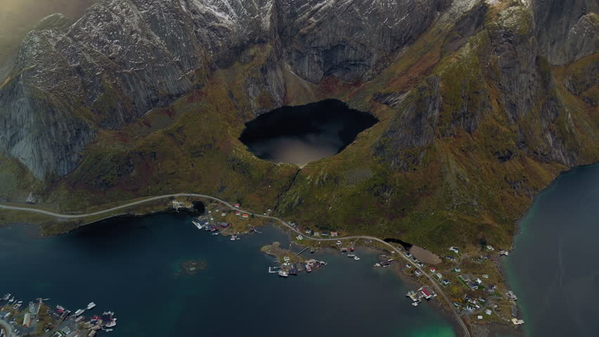View of Reinevatnet above Reine and Reinebringen hills at sunset, Lofoten islands, Revealing drone shot