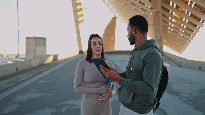 Personal trainer showing workout plan on tablet to client