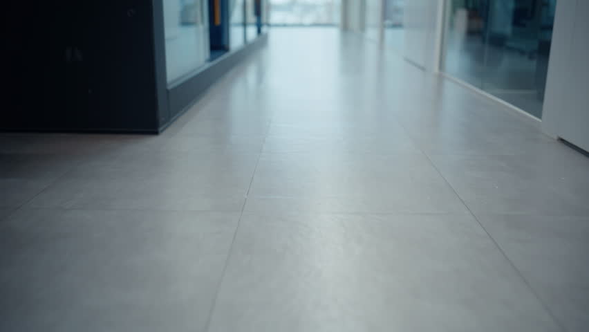Businesspeople feet walking modern empty corridor closeup. Unrecognizable business colleagues stepping on grey floor hurrying to office work. Elegant pair managers legs strolling corporate vestibule 