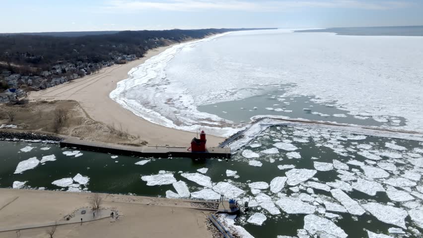 Holland, Michigan lighthouse along Lake Michigan in the winter with drone video moving in a circle wide shot.