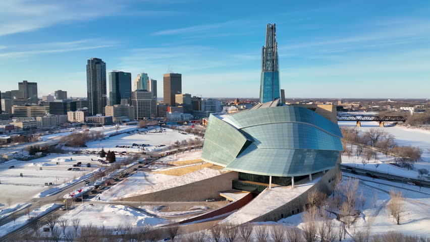 Aerial Footage Rotating Around Canadian Museum for Human Rights with Skyline in Background During Winter