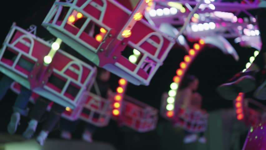 People enjoy colorful spinning carnival ride illuminated at night with vibrant lights and motion