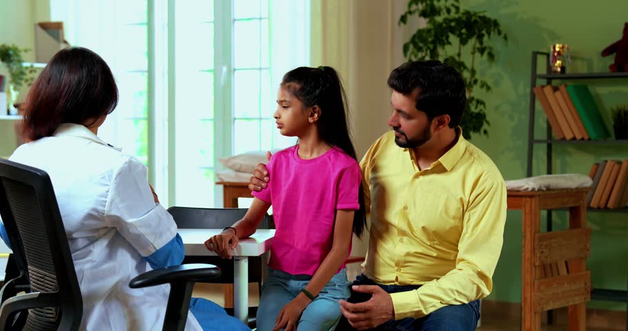 Indian Asian woman doctor pediatrician using stethoscope to examine young girl patient, caring father watches in modern clinic, ensuring a thorough medical checkup in a professional hospital, clinic