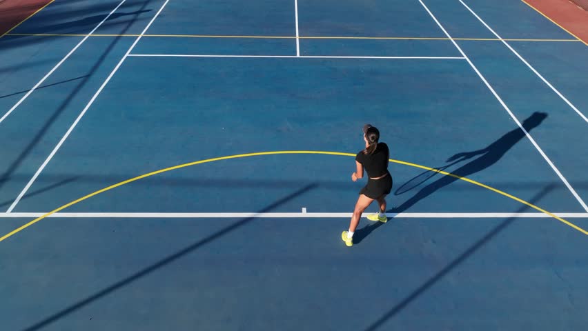 Brunette woman smashes ace tennis serve on blue clay tennis court