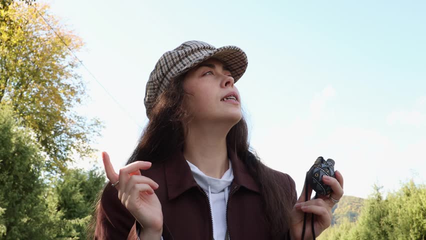 Bottom view of a young Caucasian happy woman in vintage clothes playing merrily an ocarina musical instrument. Sky in background.