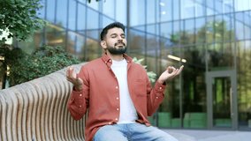 Businessman meditating with closed eyes sitting on bench on street near business office building. Handsome bearded male practices yoga breathing deeply. Calm man relieves stress, feels peace of mind - Powered by Shutterstock - Get 15% off with code: PIKWIZARD15