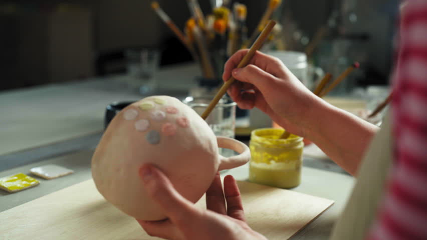 The Person is Painting Circular Patterns on a Ceramic Cup Using a Fine Brush - Close Up