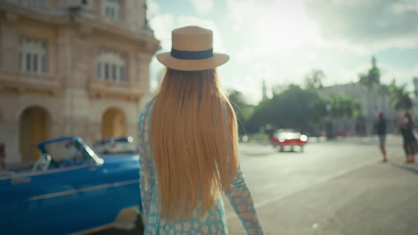 Happy woman traveler walking in center of Havana in summer day, slow motion. Tourism and traveling in Cuba in summertime, vacation and holidays, slow motion, female tourist admiring architecture