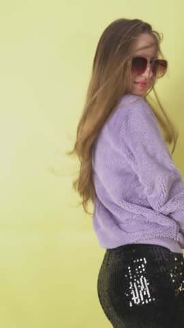 A blonde young girl dances energetically in a bright yellow studio background with copy space, perfect for creative projects and social media content.