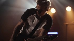 Professional male guitarist performing electric guitar during intense live rock concert, bathed in dramatic stage spotlights with passionate musical expression - Powered by Shutterstock - Get 15% off with code: PIKWIZARD15