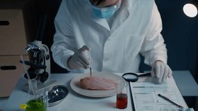 Scientist in laboratory conducts an experiment on raw chicken meat. Wearing gloves and lab coat, injects liquid from syringe into fillet. Laboratory equipment, test tubes, and microscope surround him - Powered by Shutterstock - Get 15% off with code: PIKWIZARD15