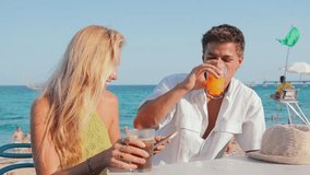 Young couple enjoying a sunny beach day while looking at their smartphones and sharing joyful moments together on the sand by the beautiful coastline with friends nearby on a lively summer afternoon - Powered by Shutterstock - Get 15% off with code: PIKWIZARD15