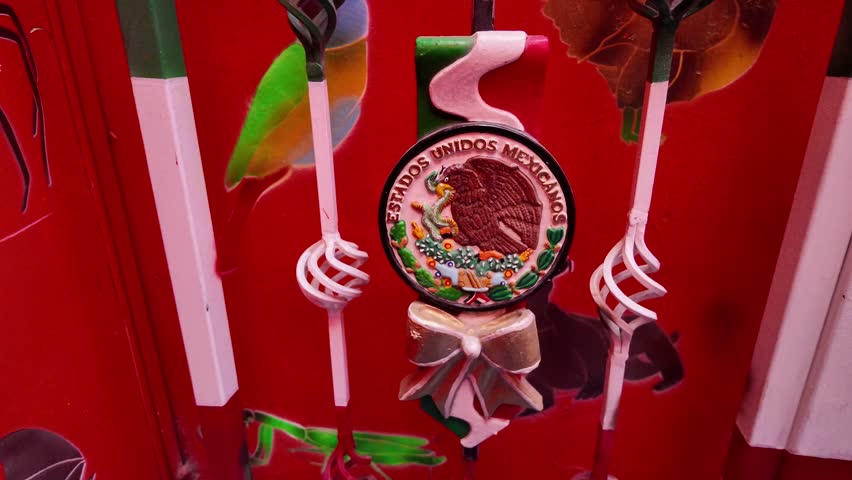 A decorative item with a Mexican eagle on it. The eagle is surrounded by a bow. The item is on a red background
