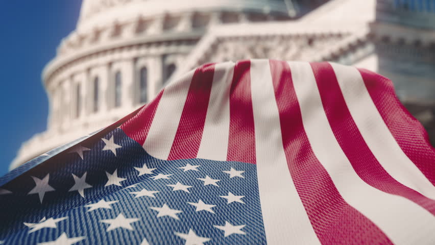 Wavy flag of United States of America waving in slow motion with the Capitol Rotunda Dome in Washington DC in the background. Official USA flag blowing in the wind