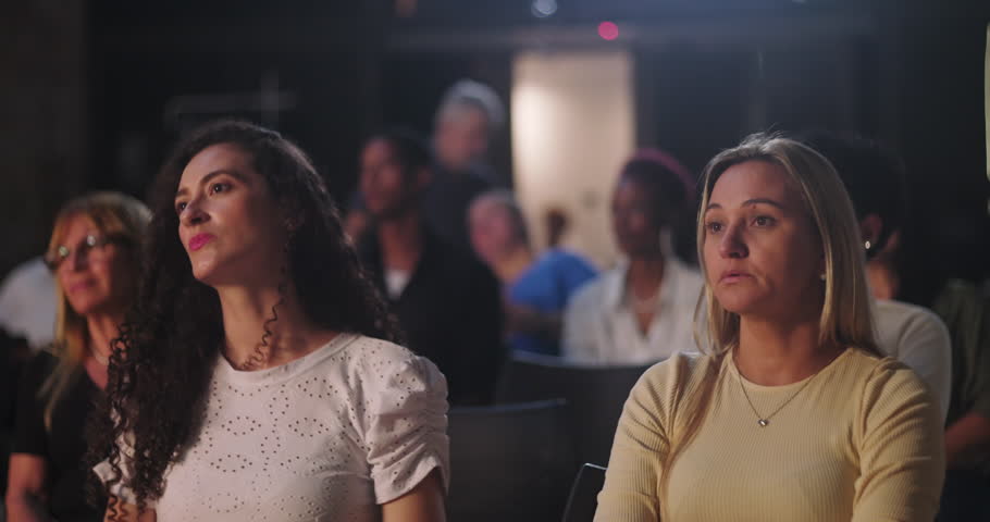 Man and woman attentively listening during a spiritual gathering, focused expressions, diverse group in audience engaged with inspiring speech and community connection