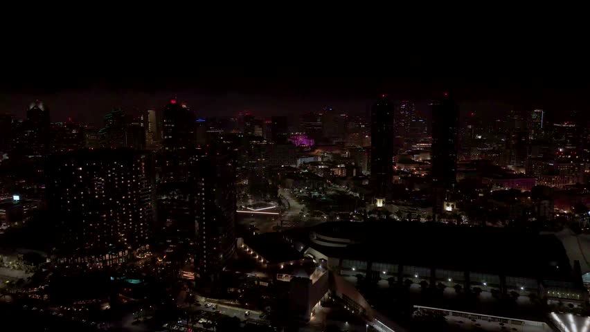 Downtown San Diego, California, USA - A Nighttime View Captures Illuminated High-rise Buildings, Streets, and a Brightly Lit Structure in the Distance - Drone Flying Forward