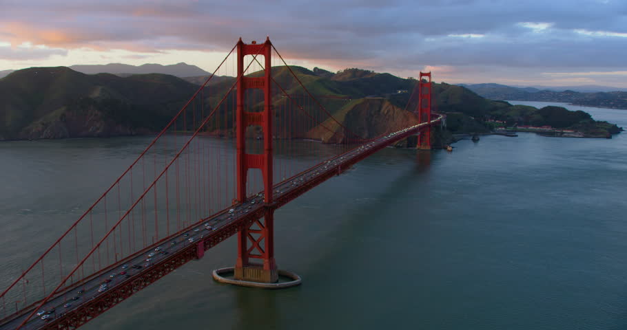Aerial view of the magnificent Golden Gate Bridge with a cargo ship passing under it. This bridge connects the San Francisco peninsula to Marin County. US route 101 and SR 1 full of cars. Shot on 8K.