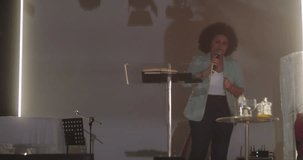Woman speaking at a podium during a church event, gesturing with one hand, holding a Bible with the other, addressing the congregation - Powered by Shutterstock - Get 15% off with code: PIKWIZARD15