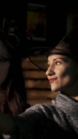 Halloween party, night, women in the twilight, in the rays of light. women with a terrible makeup in black suits witches and hats-caps do selfie on phones.