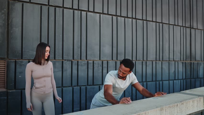 Personal trainer guiding man doing incline push-ups on wall