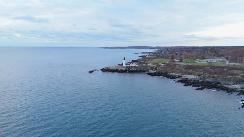 This aerial shot showcases the iconic Cape Elizabeth Lighthouse in Portland, Maine, highlighting the serene waters and coastal beauty at sunset, ideal for nature lovers and outdoor enthusiasts