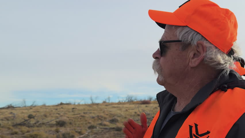 Old man Mule Deer hunter giving instructions to his mates in a field during the day in Southwest Colorado, USA, medium shot