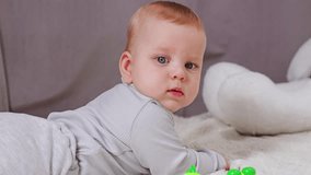 A small child with big blue eyes lies on a soft blanket. The baby has red hair. The baby is looking at the camera. The baby is playing lying on the floor on the background plush toy
 - Powered by Shutterstock - Get 15% off with code: PIKWIZARD15