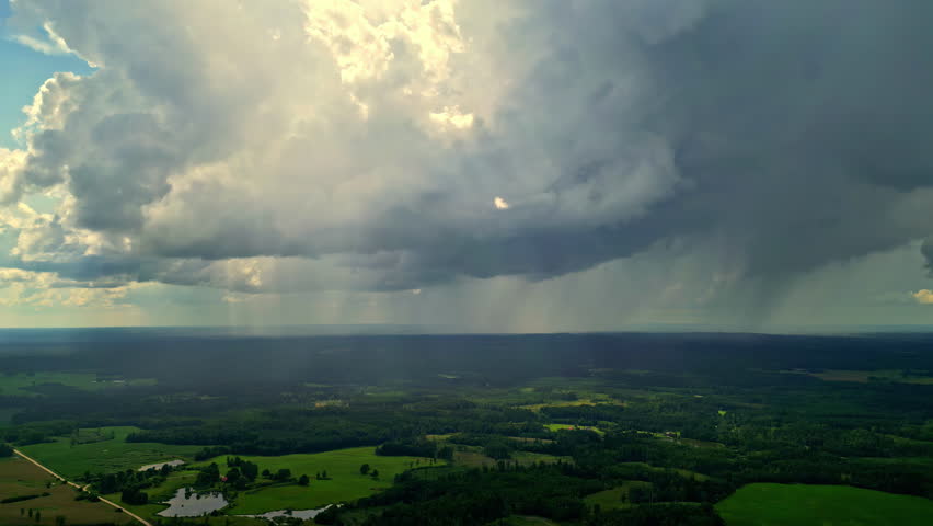 Rain clouds over countryside landscape, high aerial shot of storm weather