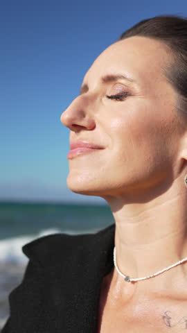Woman Beach Portrait Relaxing Sun Woman Beach Ocean Waves - A woman sits on a rock on a beach as ocean waves crash against the shore.