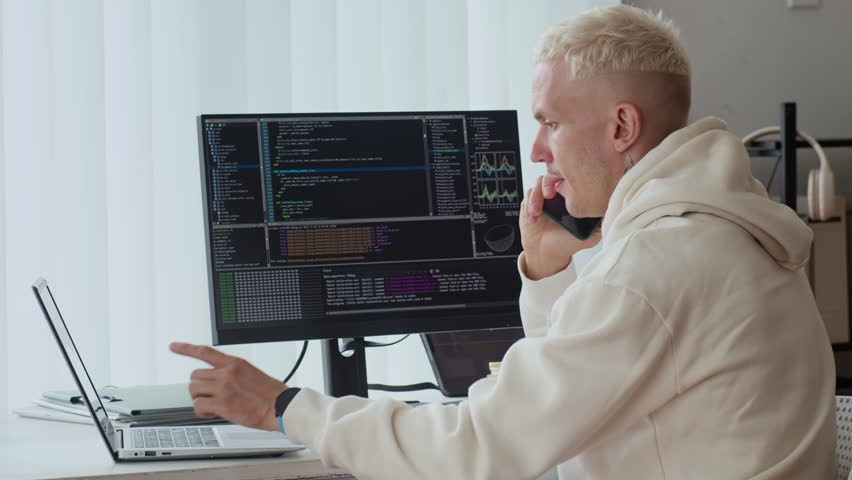 Side view of male Caucasian coder in relaxed casualwear consulting on smartphone while having problem with script on gadgets