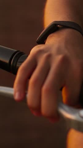 Vertical close-up of a biker's hand gripping the gas lever of a motorcycle at sunset, starting the engine, adjusting gas on moto bike.