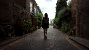 Follow footage rear view of silhouette of unrecognizable young woman in shorts walking forward in archway in old part of town. tourist traveling in city. - Powered by Shutterstock - Get 15% off with code: PIKWIZARD15