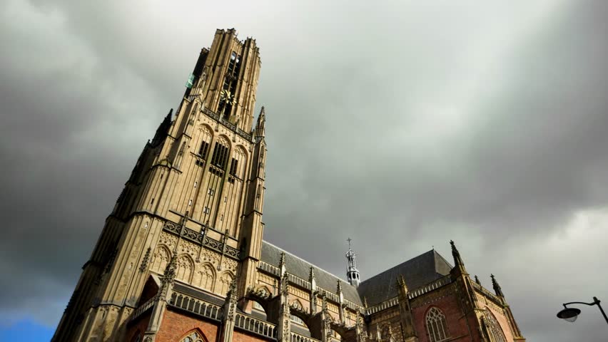 A close-up shot of the towering Eusebius Church in Arnhem, highlighting its intricate Gothic details against a cloudy sky. Location: Arnhem, Netherlands (Arnhem, Nederland).