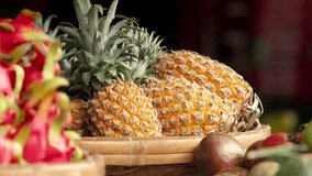 ripe juicy pineapples lie on a counter at an open market with a dragon fruit in the foreground out of focus. - Powered by Shutterstock - Get 15% off with code: PIKWIZARD15