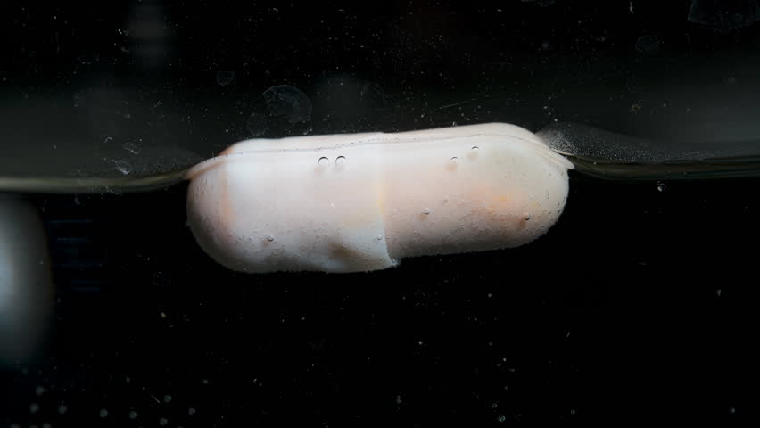 Pill dissolving in liquid, showing bubbles forming around it as it breaks down