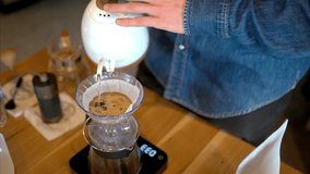 Close up of a man brewing pour-over drip coffee in a slow, circular motion on a wooden table - Powered by Shutterstock - Get 15% off with code: PIKWIZARD15