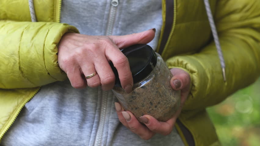 Girl Opens Jar With Food For Wild Birds In Forest